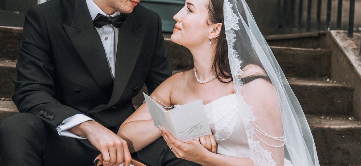 Bride and groom holding vow books on steps